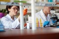 Young chemistry students are pipetting and microscoping in a laboratory. Science, chemistry, lab, people Royalty Free Stock Photo