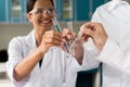 Young chemists clinking test tubes with reagents in lab