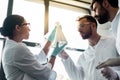 Young chemists in eyeglasses and white coats making experiment in laboratory