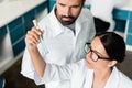 Young chemists in white coats examining test tube with reagent in chemical lab