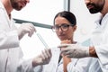 Young chemists in white coats looking at test tube with reagent in lab