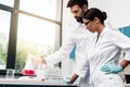 Young chemists in white coats making experiment while working in laboratory