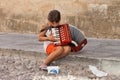 Young child beggar, playing music in the streets