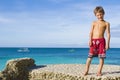 Young child boy on rocks on tropical sea backgroun