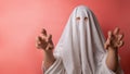Young child dressed in a ghost costume for halloween on pink background