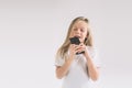 Young child eating a chocolate bar. Blondy girl isolated on white background. Royalty Free Stock Photo