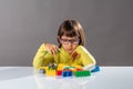 Young child with eyeglasses thinking about organizing toys with imagination