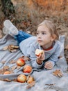 Young child girl lies on a plaid and eating apple on a picnic Royalty Free Stock Photo