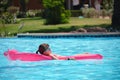 Young child girl relaxing on summer sun swimming on inflatable air mattress in swimming pool during tropical vacations Royalty Free Stock Photo