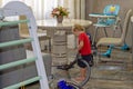 A young child helps her mother do the cleaning vacuums the floor in the room.