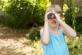 Young child kid uses binoculars to explore the garden, looking for something through the monocular, copy space searching, seeking Royalty Free Stock Photo