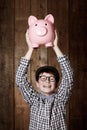 Young child, piggy bank and happy in portrait in studio, money saving and cash savings in youth with retro fashion. Boy