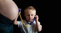 Young child playing doctor listening to pregnancy bump