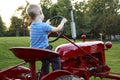 Young child pretending to drive a red tractor