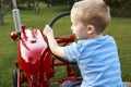 Young Child pretending to drive a red tractor