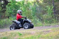 A young child rides a quad in a forest