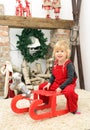 Young child sit indoor on sledge at christmas Royalty Free Stock Photo