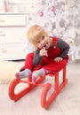 Young child sit indoor on sledge at christmas Royalty Free Stock Photo