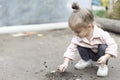 A young child sits on the ground, playing with soil and exploring its texture. A simple and authentic moment of Royalty Free Stock Photo