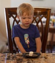 Young child sitting at a table waiting patiently for a marshmallow