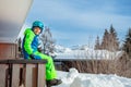 Young child in ski outfit sit on balcony rail at winter house Royalty Free Stock Photo