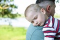 A young child is sleeping in his father`s safe and protective embrace while on walk. Portrait of cute adorable blond