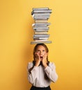 Young child student worried due to too much books to read and study. Yellow background Royalty Free Stock Photo