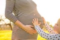 Young child touching the pregnant belly of her mother in beautiful evening sunlight Royalty Free Stock Photo