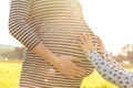 Young child touching the pregnant belly of her mother in scenic afternoon sunlight Royalty Free Stock Photo