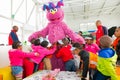 Young children embracing a large plush pink Cookie Monster character