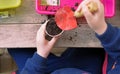 Young children learning how to plant seeds in garden. Narrow depth of field of hands holding seeds and black soil in pot.