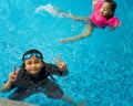 Young children in the pool. Kids having fun in swimming pool.  Wearing goggles on forehead on summer vacation Royalty Free Stock Photo