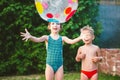 Young children siblings play large inflatable beach ball in courtyard of house in swimming pool. theme of heat and water games,