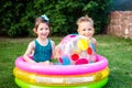 Young children siblings play large inflatable beach ball in courtyard of house in swimming pool. theme of heat and water games, Royalty Free Stock Photo