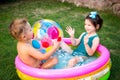 Young children siblings play large inflatable beach ball in courtyard of house in swimming pool. theme of heat and water games,