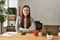 Young chinese business worker wearing business style sitting on desk at office happy face smiling with crossed arms looking at the Royalty Free Stock Photo