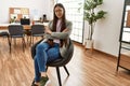 Young chinese businesswoman smiling happy sitting on the chair with arms crossed gesture at the office Royalty Free Stock Photo