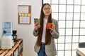 Young chinese businesswoman using smartphone and drinking coffee at the office Royalty Free Stock Photo
