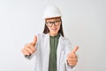 Young chinese engineer woman wearing coat helmet glasses over isolated white background approving doing positive gesture with Royalty Free Stock Photo