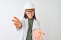 Young chinese engineer woman wearing coat helmet glasses over isolated white background looking at the camera smiling with open Royalty Free Stock Photo