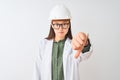 Young chinese engineer woman wearing coat helmet glasses over isolated white background looking unhappy and angry showing Royalty Free Stock Photo