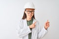 Young chinese engineer woman wearing coat helmet glasses over isolated white background smiling and looking at the camera pointing Royalty Free Stock Photo