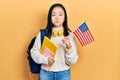 Young chinese girl exchange student holding america flag puffing cheeks with funny face