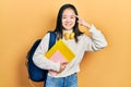 Young chinese girl holding student backpack and books smiling pointing to head with one finger, great idea or thought, good memory Royalty Free Stock Photo