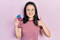 Young chinese girl playing colorful puzzle cube intelligence game smiling happy and positive, thumb up doing excellent and Royalty Free Stock Photo
