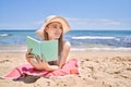 Young chinese girl reading book lying on the towel at the beach Royalty Free Stock Photo