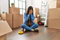 Young chinese girl sitting on the floor at new home with sad expression covering face with hands while crying Royalty Free Stock Photo
