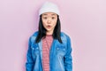 Young chinese girl wearing cute wool cap scared and amazed with open mouth for surprise, disbelief face Royalty Free Stock Photo
