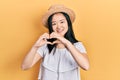 Young chinese girl wearing summer hat smiling in love showing heart symbol and shape with hands Royalty Free Stock Photo