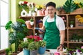 Young chinese man florist using touchpad writing on notebook at flower shop Royalty Free Stock Photo